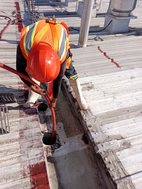 Construction worker wearing orange safety vest and red hard hat working on wooden dock or pier structure